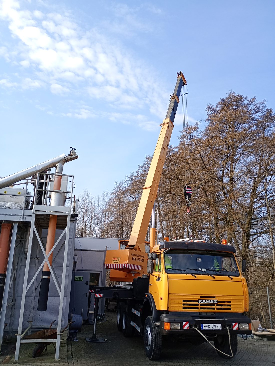 Kamaz z wysuniętym wysięgnikiem w sąsiedztwie budynków